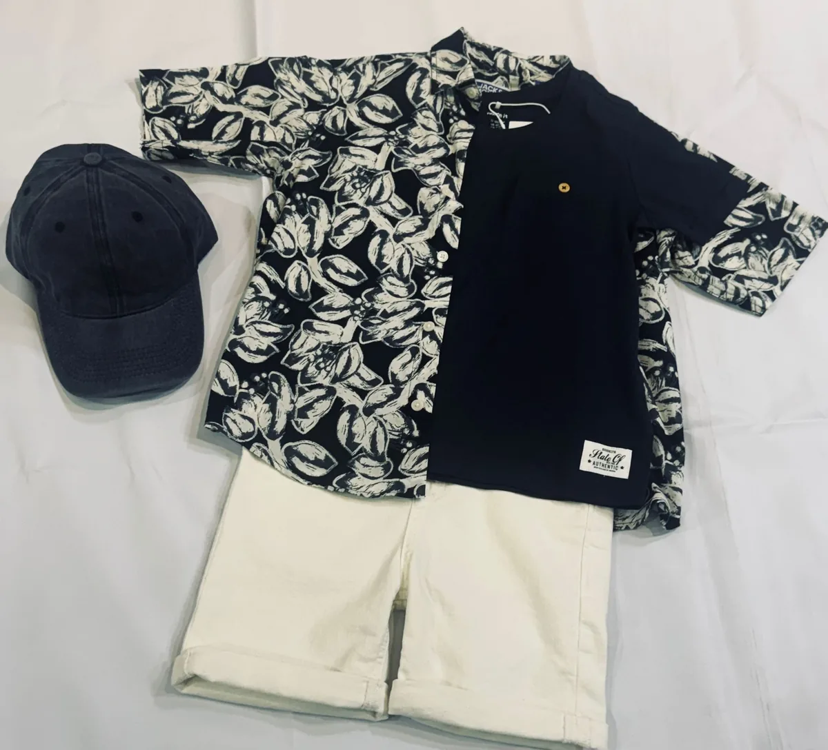 Conjunto preparado: camisa estampada, pantalón claro y gorra.