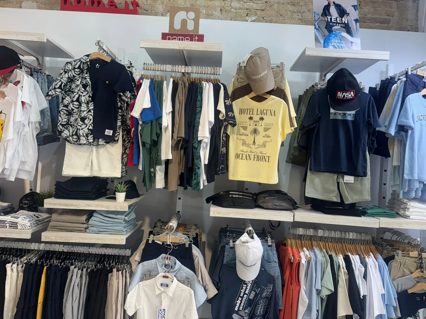 Expositor de pared con camisetas y conjuntos colgados.