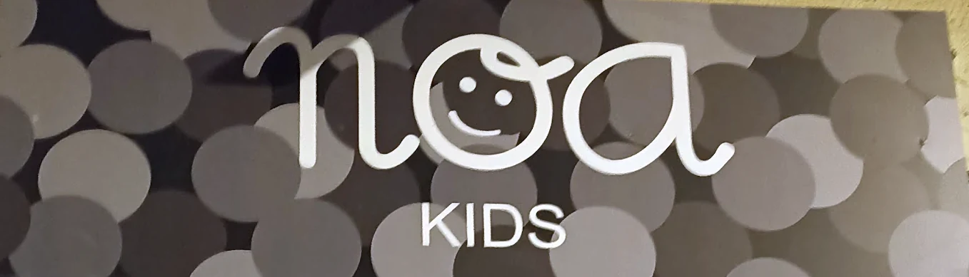 Rótulo de la tienda: noa, con una carita dentro de la o, y KIDS debajo.